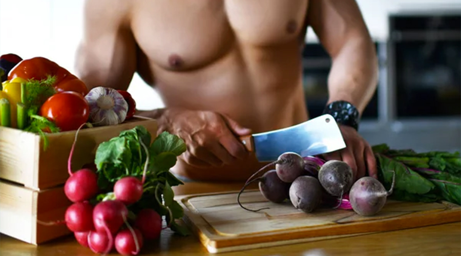 Muscular sport man standing on kitchen cutting beetroot