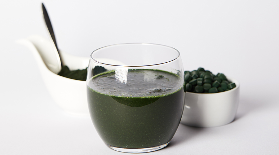 Spirulina drink in glass, spoon, spirulina powder