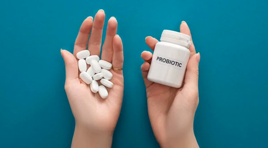 woman holding white probiotic container and pills in hands