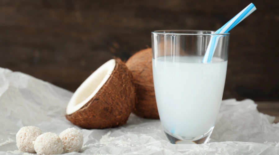 Glass of tasty coconut water on table