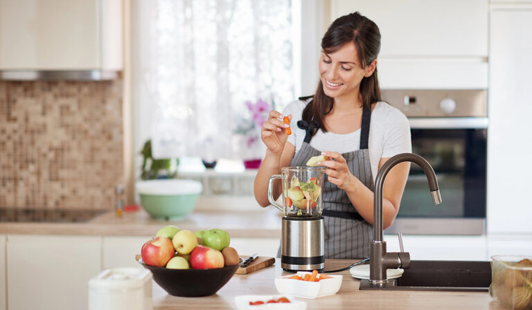 Woman blending fruits and veggies in the kitchen